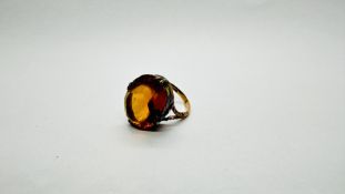 A VINTAGE 9CT GOLD RING SET WITH OVAL AMBER COLOURED GLASS IN A RAISED SETTING.