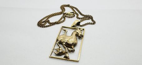 A 9CT GOLD OPEN WORK HORSE PENDANT H 4.2CM X W 2.5CM ON A YELLOW METAL FLAT LINK CHAIN, L 38CM.