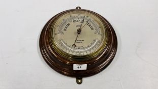 A CIRCULAR OAK MOUNTED MARINE ANEROID BAROMETER, THE DIAL INSCRIBED JOHN BARKER & CO.