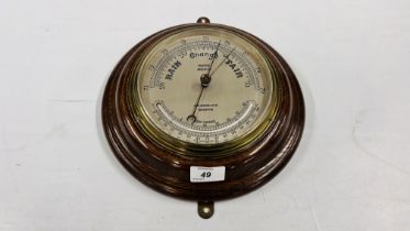 A CIRCULAR OAK MOUNTED MARINE ANEROID BAROMETER, THE DIAL INSCRIBED JOHN BARKER & CO.