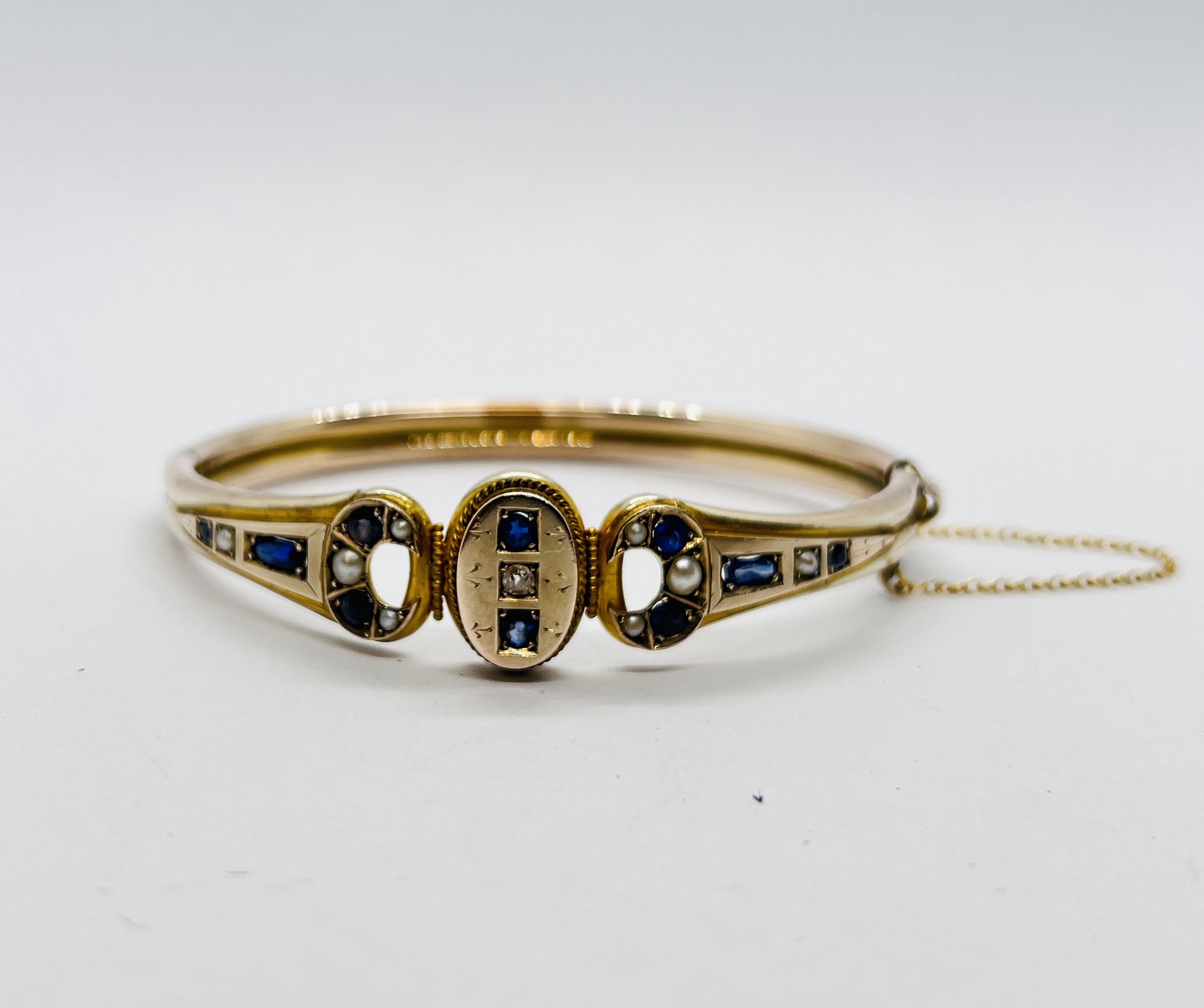 AN IMPRESSIVE EDWARDIAN HINGED YELLOW METAL BANGLE AND SAFETY CHAIN INSET WITH A DIAMOND,