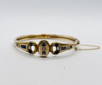 AN IMPRESSIVE EDWARDIAN HINGED YELLOW METAL BANGLE AND SAFETY CHAIN INSET WITH A DIAMOND,