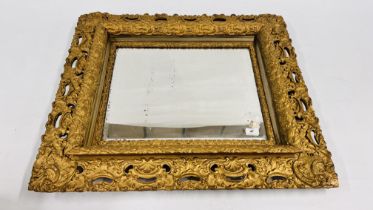 AN ORNATE ANTIQUE DECORATIVE GILT FRAMED WALL MIRROR 80CM X 69CM.