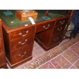 An antique pedestal desk with seven drawers to the