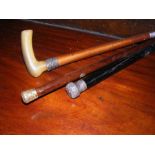A silver topped walking cane together with two oth