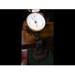 A circular aneroid barometer on cast iron figure s