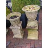 A pair of garden urns on plinths (one incomplete)