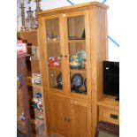 A light oak cabinet with glazed upper half and cup
