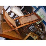 A fold-up steamer chair with cane work seat and ba