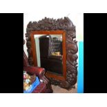 An antique wall mirror with extensively carved sur