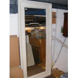 A large bevelled wall mirror in painted white meta