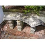 A large stone garden bench on three plinth support