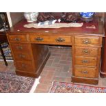 An antique oak pedestal desk with nine drawers to