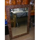 A bevelled wall mirror in carved oak frame