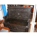 An antique carved oak monks bench with lift up sea