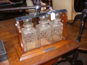 A three bottle tantalus in an oak and chrome stand