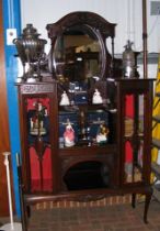 An Edwardian display cabinet with oval mirrored ba