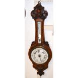 A Victorian oak barometer/thermometer in carved su