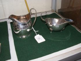 A silver cream jug together with sauce boat