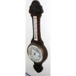 A barometer/thermometer with carved oak surround