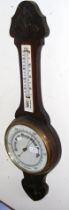 A barometer/thermometer with carved oak surround