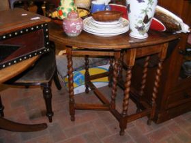 A drop-leaf oak table on barley twist supports