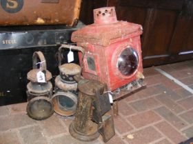 An old red painted railway lamp together with thre