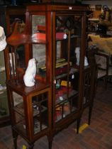 An Edwardian display cabinet with shaped upper sec
