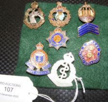 Six metal and one mother-of-pearl lapel badges,