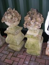 A pair of decorative fruit basket urns on plinths