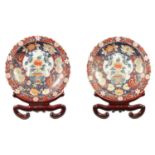 A LARGE PAIR OF 20TH CENTURY JAPANESE IMARI CHARGERS WITH STAINED WOOD STANDS