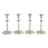 A FINE SET OF FOUR GEORGE III LARGE CAST SILVER TABLE CANDLE STICKS IN THE ROCOCO MANNER