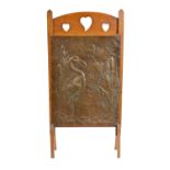 AN ARTS AND CRAFTS PRESSED BRASS AND OAK FIRE SCREEN