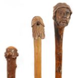TWO MASK HEAD CARVED WOOD WALKING STICKS AND A RIDING CROP