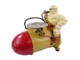 A Michelin Man air compressor pump in the form of a Michelin Man sitting on an artillery shell, 30cm