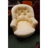 Cream upholstered button back elbow chair on curved legs and brass casters