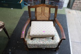 1930s Low upholstered cane backed elbow chair and a upholstered footstool with squat paw feet