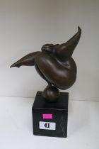 Bronze sculpture depicting a rotund lady balancing on a spherical object, mounted on slate base,