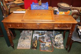 Large Oak sloped top desk with turned handles supported on turned legs and casters