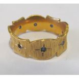 A gold coloured band set blue stones marked 18k 1 stone missing