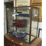 A table top display case with 2 glass shelves and door to each end (one locked)