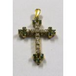 A cross set diamonds and green stones