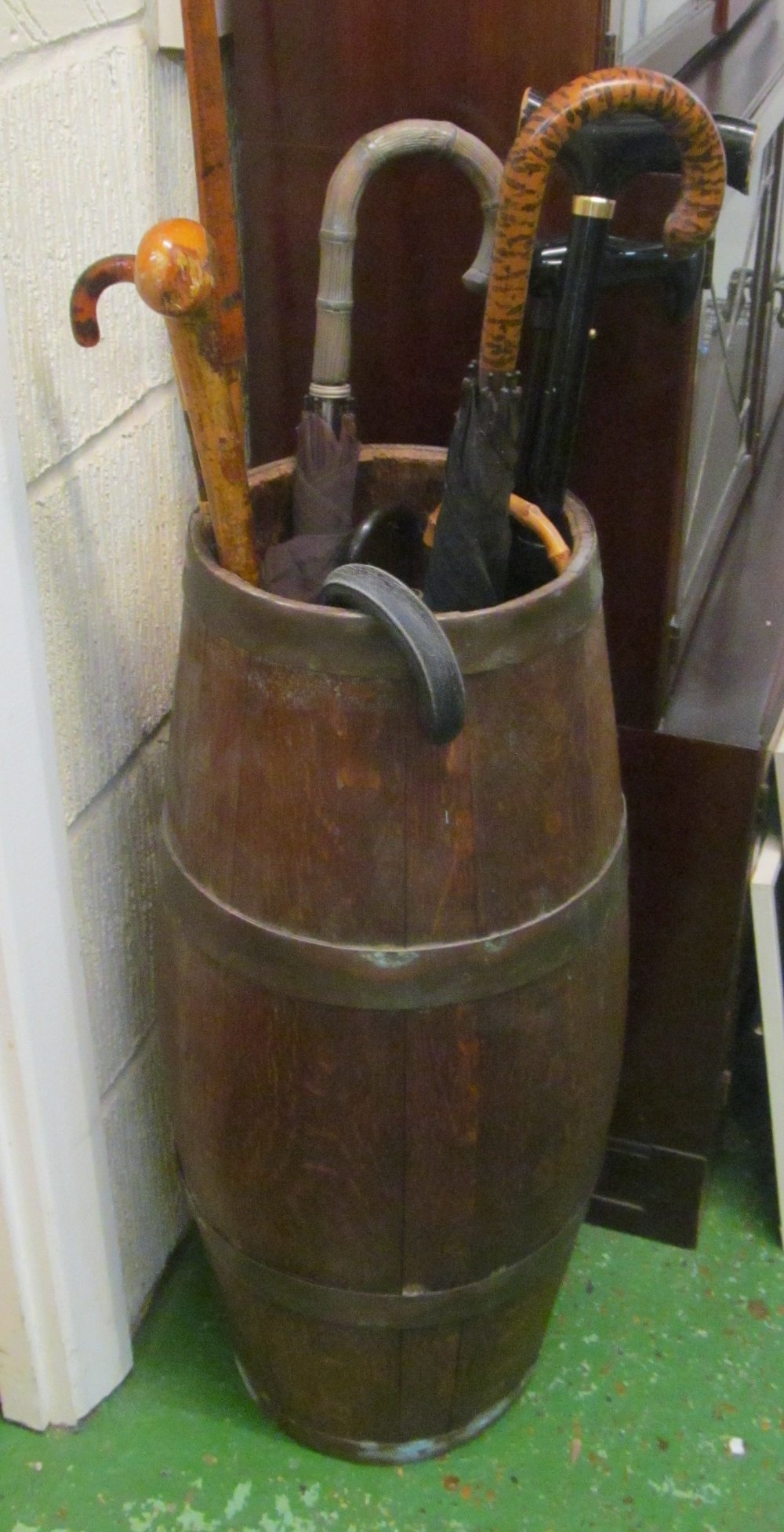 A tall oak barrell with brass bindings, various sticks and umbrellas