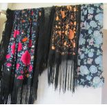 A black textile with long fringing and embroidered floral design, another similar with peach