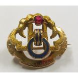 A gold coloured brooch enamel and red stone