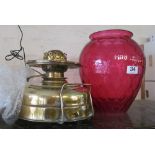 A brass paraffin lamp with large honeycomb cranberry shade