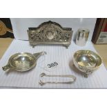 A small silver tea strainer with bowl, silver pencil sharpener, silver tongs and silver paper