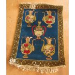 A small rug blue ground with eastern jugs and vase within green border