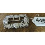 A pierced silver buckle with mask heads and scroll design