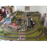 A railway layout of trains, carriages, goods wagons, buildings, cars, buses, fencing etc